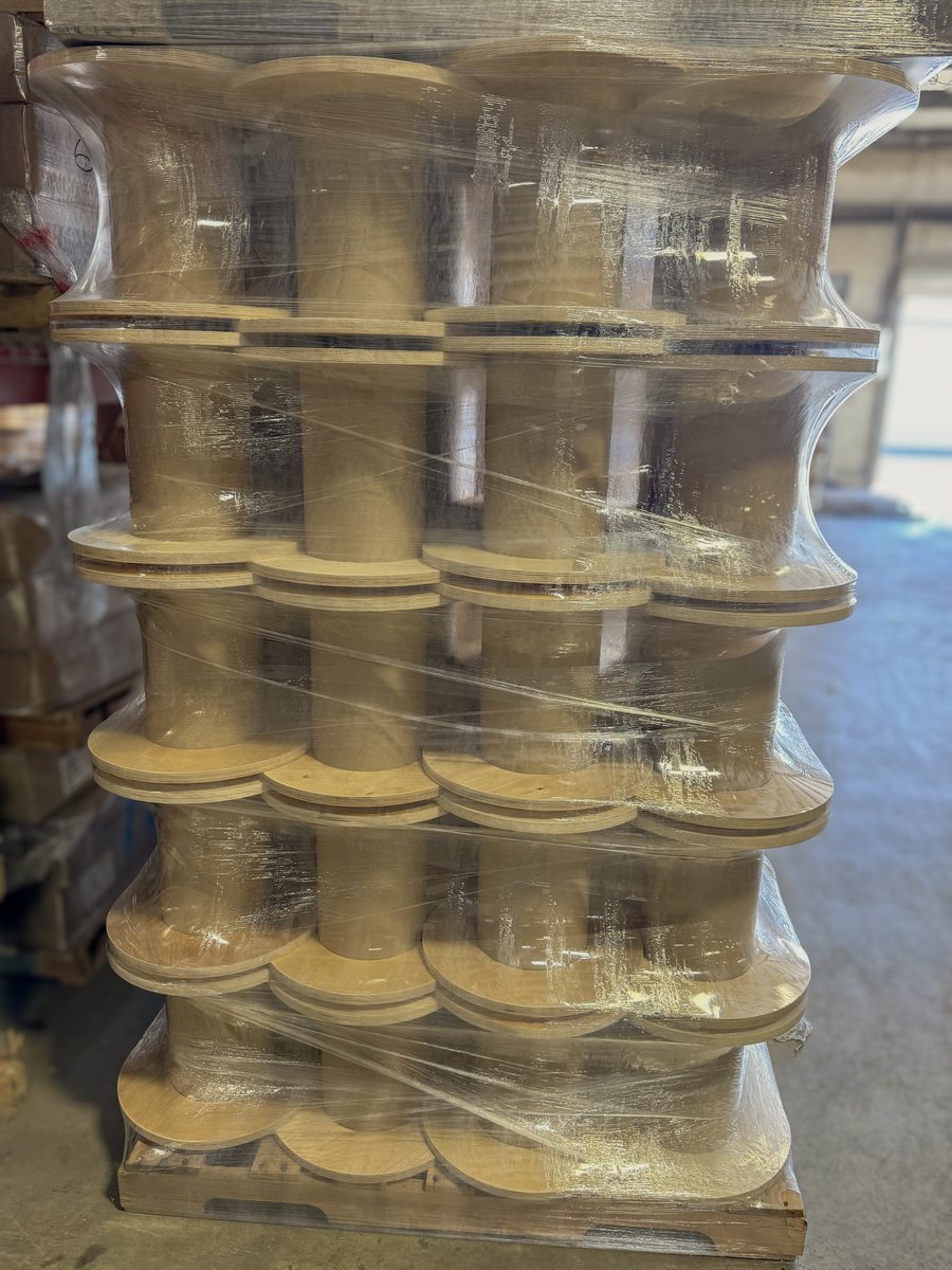 A shrink-wrapped pallet of cable reels with cardboard cores and plywood flanges