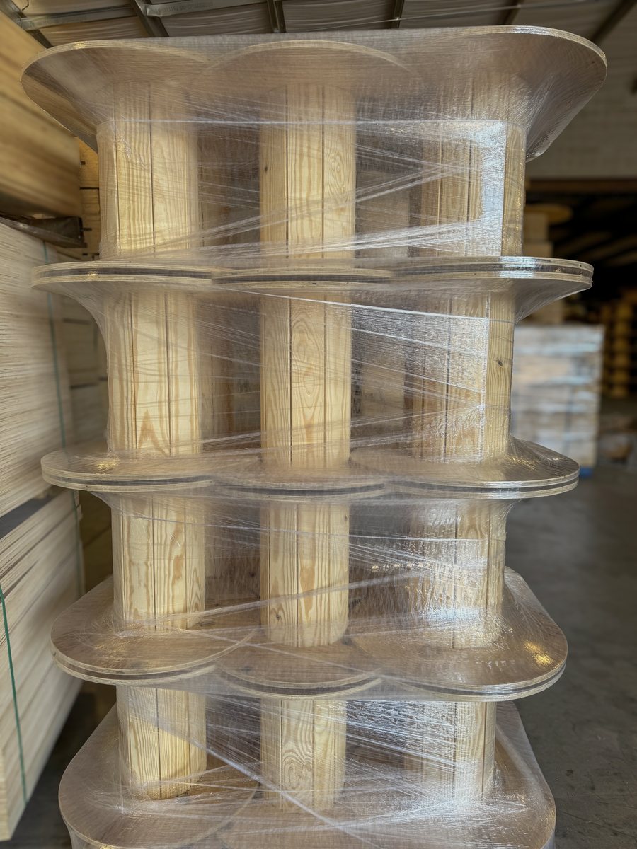A shrink-wrapped stack of nailed wood cable reels with pine plank barrels